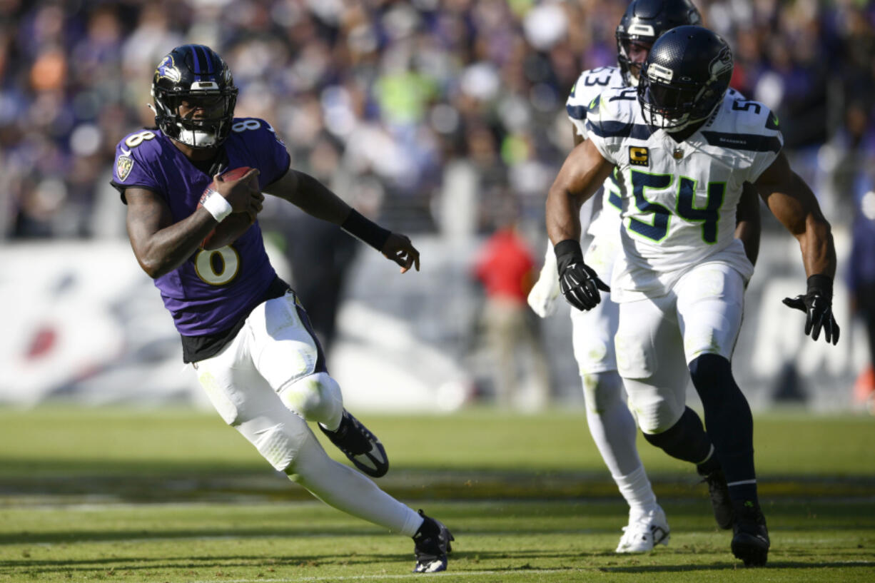 Baltimore Ravens quarterback Lamar Jackson (8) scrambles up field away from Seattle Seahawks linebacker Bobby Wagner (54) during the first half of an NFL football game, Sunday, Nov. 5, 2023, in Baltimore.