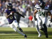 Baltimore Ravens quarterback Lamar Jackson (8) scrambles up field away from Seattle Seahawks linebacker Bobby Wagner (54) during the first half of an NFL football game, Sunday, Nov. 5, 2023, in Baltimore.