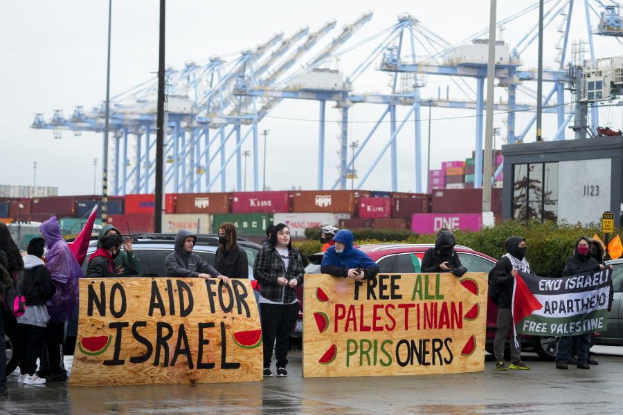 Protesters hold up large wooden signs as they block the main Port of Tacoma entrance to delay the loading of the Cape Orlando vessel, Monday, Nov. 6, 2023, in Tacoma, Wash.