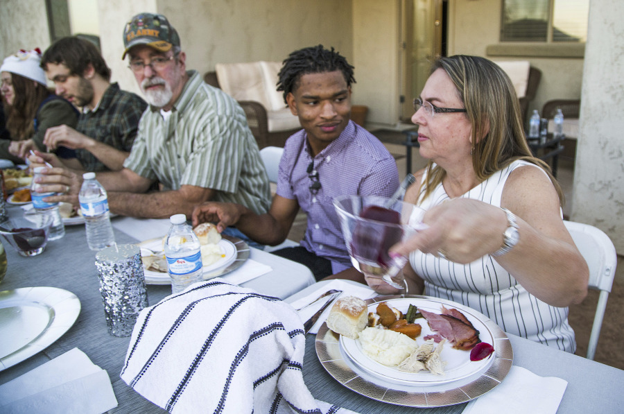 Jamal Hinton, center, Wanda Dench, right, and her family and friends, have Thanksgiving dinner at Dench&rsquo;s home on Nov. 24, 2016, in Mesa, Ariz.