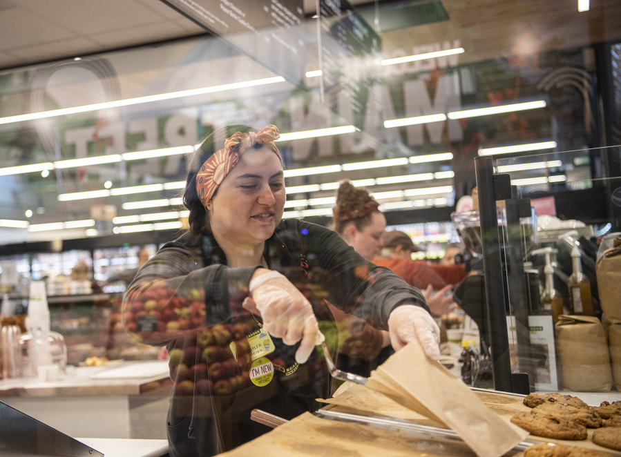 New Seasons Market bakery clerk Kalyea Fanony puts a cookie into a paper bag on Oct. 18 during the grand opening of the downtown Vancouver store.