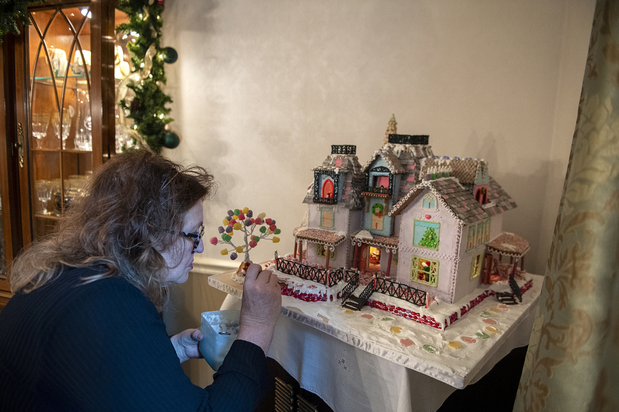 Cathy Ramer of Felida puts the finishing touches on her gingerbread house. She&rsquo;s been designing and constructing ever-more-ambitious gingerbread structures since 1982, installing lighting systems and even decorating the interior with miniatures.