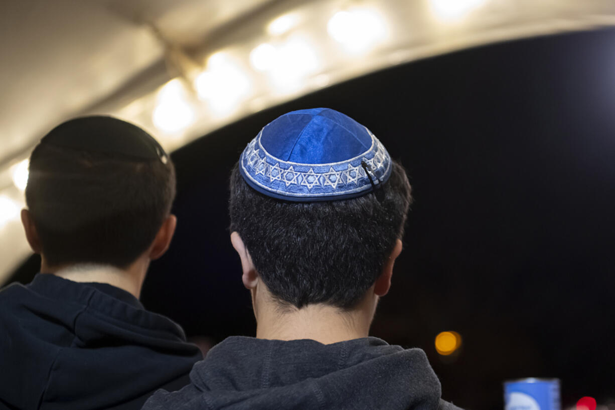 Xavier Duval of Vancouver, left, joins his brother Alexander, 13, as they wear their yarmulke while helping collect canned food for local families at Esther Short Park on Thursday evening, Dec. 7, 2023.
