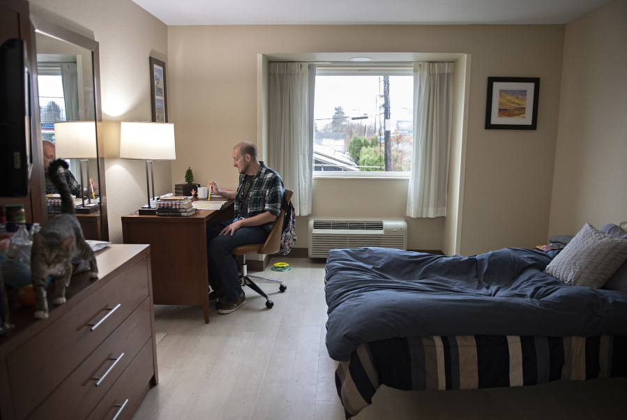 Tom Harvey, a resident of Central City Concern&rsquo;s Evergreen Crossing who is finding his way out of homelessness, tackles a word search as he takes a break in his room.