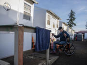 Jimmy Howland of Vancouver, who had his leg amputated in 2020, navigates the small ramp he built for his unit at Hope Village in Vancouver.  At top, a  man has his vitals checked at the Evergreen Crossing respite medical clinic in Portland.