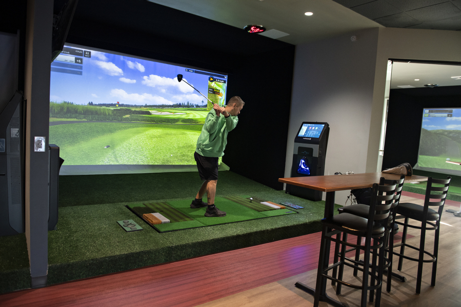 Steve Hilken, one of the owners of Courses Golf &amp; Grill opening in east Vancouver, takes a swing as he demonstrates a new golf simulator last week.
