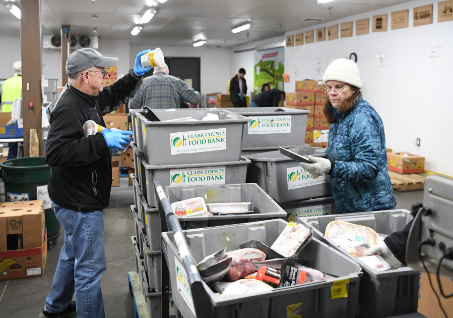 Volunteers Rob Fleskes, left, and Laurie Southwell, both of Vancouver, sort bins of frozen meat Tuesday at the Clark County Food Bank.