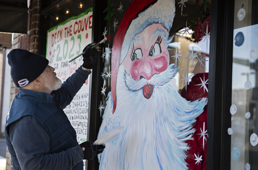 Artist Kent Huggins puts the finishing touches on a painting of Santa Claus while creating holiday scenes on businesses&rsquo; windows in downtown Vancouver for free, as seen at Center Stage Clothiers on Wednesday afternoon.