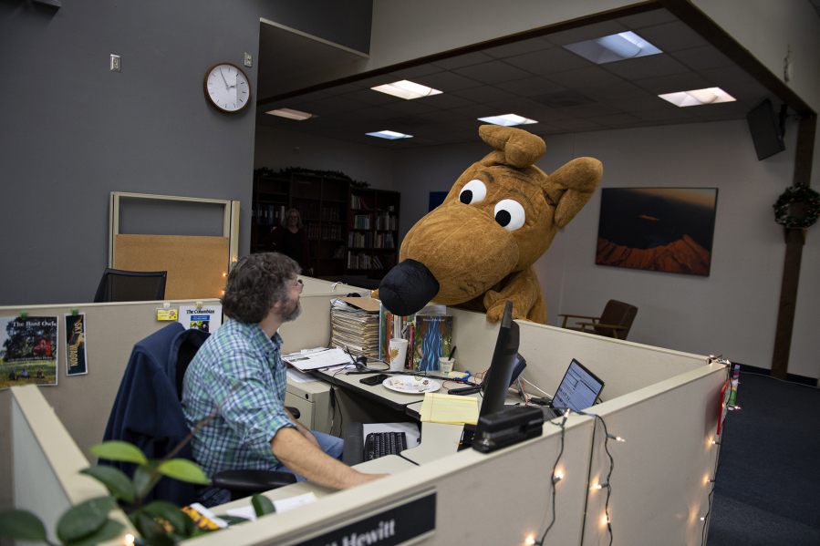 Columbo, The Columbian's weather dog and mascot, gets the scoop from reporter Scott Hewitt while visiting the newsroom Dec. 14.