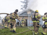 Firefighters carry a hose into a burning house Wednesday during a Clark-Cowlitz Fire Rescue training exercise in Ridgefield. For seven new firefighter/paramedics, the training marked their last exercise before graduating from the fire academy and joining the agency&rsquo;s ranks.