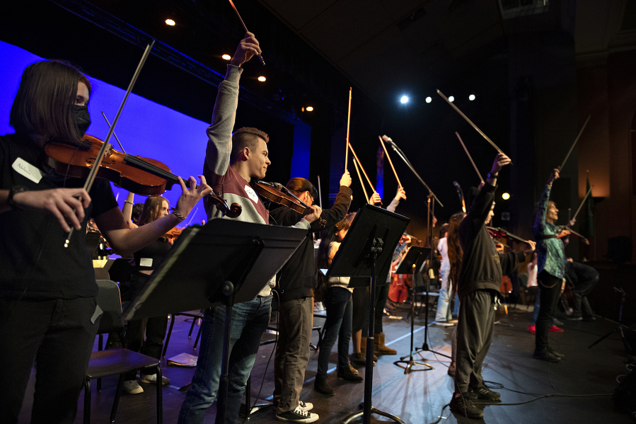 Vancouver School of Arts and Academics students conclude a practice performance with their bows in the air while joined by international recording artist and Emmy award-winning composer Mark Wood, right, in their school&rsquo;s auditorium Jan. 31. Wood is an original member of the multiplatinum selling Trans-Siberian Orchestra and creator of the revolutionary Viper electric violin. He visited VSAA with his groundbreaking music education program Electrify Your Strings!