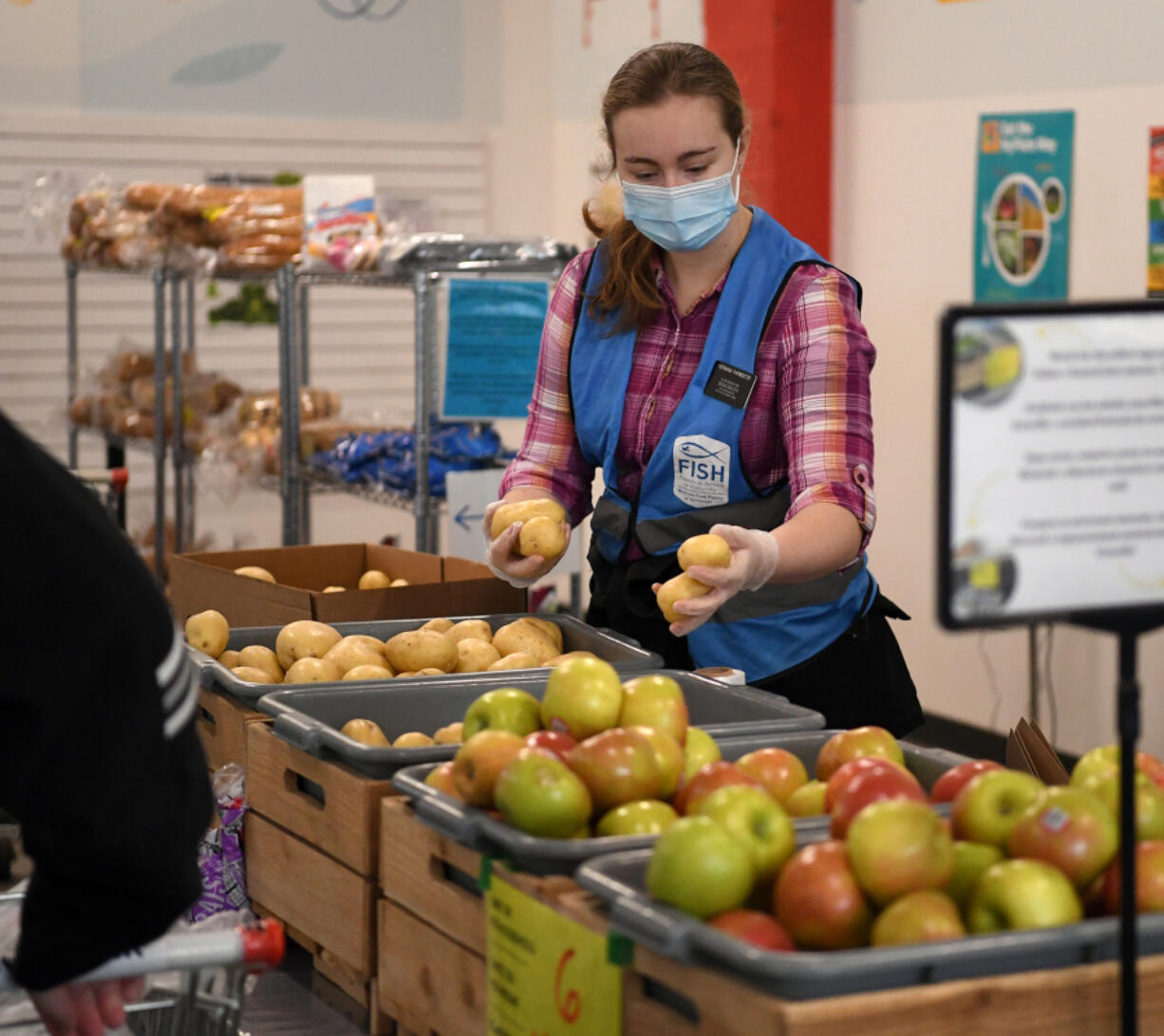 Volunteer Alisandra Parmenter restocks potatoes Friday at FISH of Vancouver. The organization set a record for number of families served this week.
