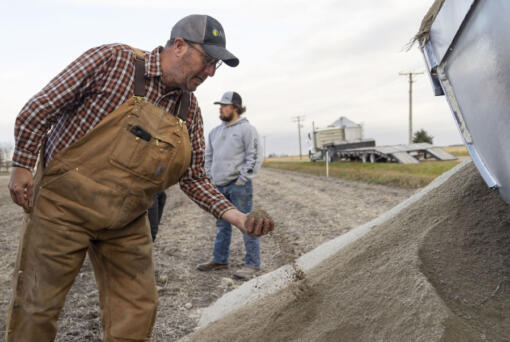 Farmer Erich Schott takes a look at the concrete powder that was spread across his soybean field on Nov. 10, 2023, at Schott Farms in Buckingham, Illinois. The concrete will be tested for efficacy in removing carbon dioxide compared with agricultural lime.