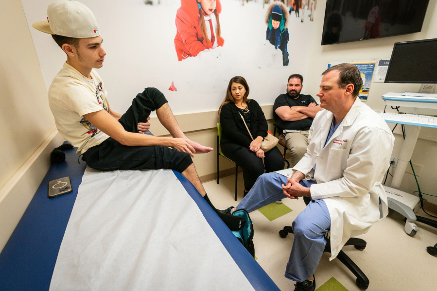 J. Todd Lawrence, an orthopaedic surgeon, examines Anthony Greco&Dagger;&shy;s leg during a Nov. 10 appointment at Children&rsquo;s Hospital of Philadelphia. His parents, Krystine Greco and Carl Wardell, look on. Lawrence operated on Anthony&rsquo;s leg after he suffered a compound fracture when he hit a pothole and flew off an electric scooter back in August. (Jessica Griffin/The Philadelphia Inquirer/TNS) (Steven M.