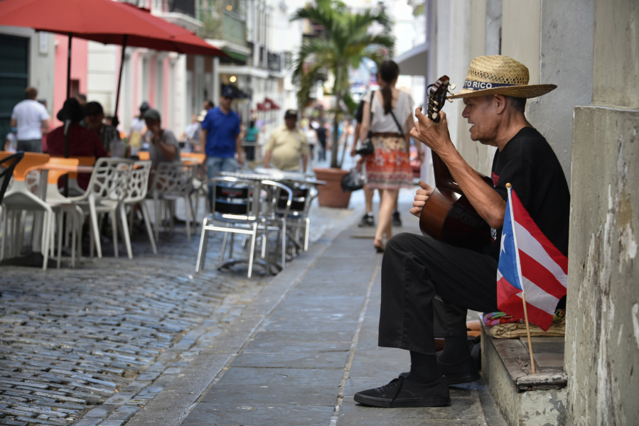 A street performer serenades diners in San Juan, Puerto Rico. Puerto Rico boasts colorful colonial architecture, and free-roaming dogs, horses and chickens lend the island an international feel.