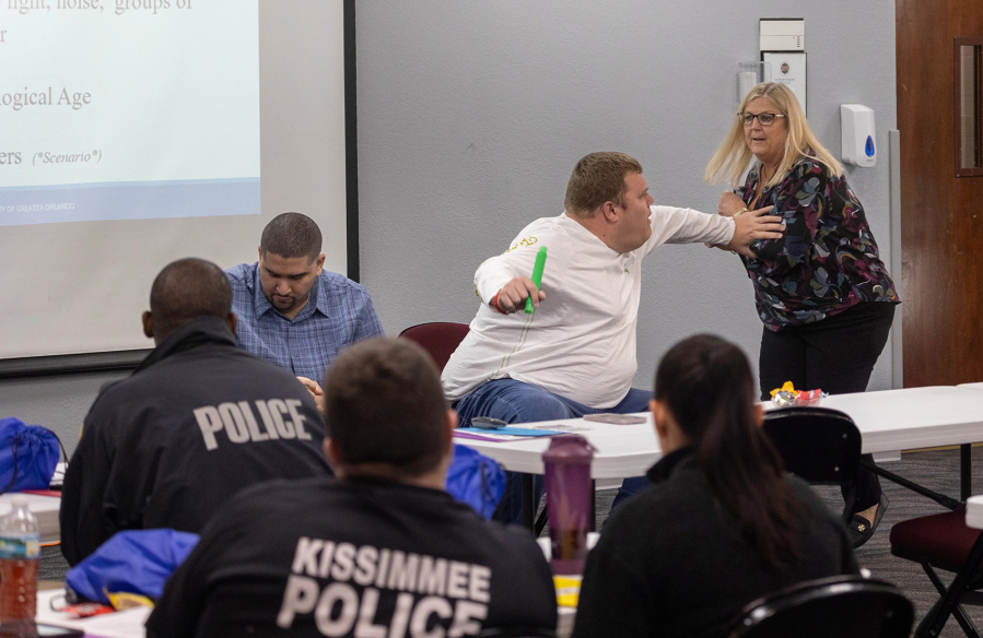 Autism Society of Greater Orlando President, Donna Lorman, right, demonstrates a de-escalation technique with her autistic son Drew Lorman, center, 31 during a first responder training session at the Civic Center in Kissimmee, Florida, Tuesday, Dec. 19, 2023. (Willie J.