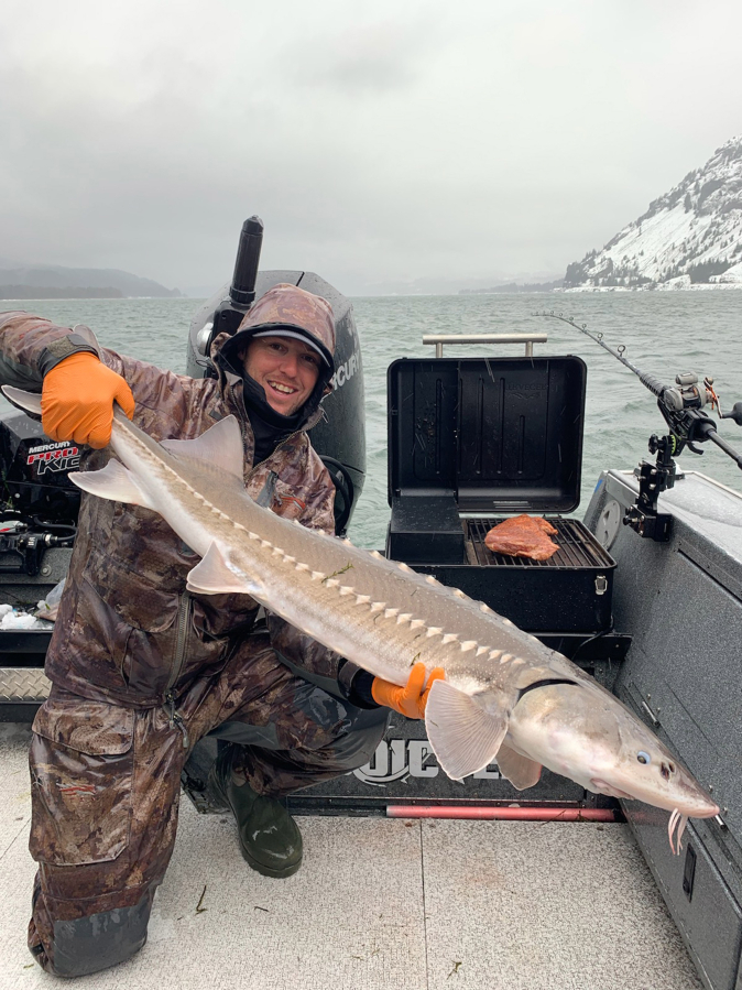 A keeper sturgeon is held by guide Cameron Black. Even when the wind howls, Black knows the Gorge well enough to get his clients on to sturgeon in quiet waters.