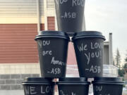 Washougal High School leadership students show off hot chocolate cups, decorated with personalized thank-you messages, before giving them to bus drivers Nov. 21.