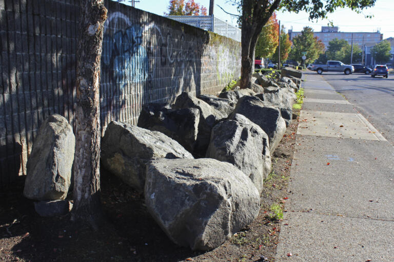 Roughly 30 large boulders occupy the narrow strip of land between a sidewalk and a parking lot wall in Portland, Ore., on Oct. 17, 2023. The boulders were installed sometime after late July at the site of a former homeless encampment to prevent tents from being set back up. The encampment was cleared several times over the course of the year. Cities across the U.S. are struggling with and cracking down on tent encampments as the number of homeless people grows, largely due to a lack of affordable housing. Homeless people and their advocates say sweeps are cruel and costly, and there aren't enough homes or beds for everyone.