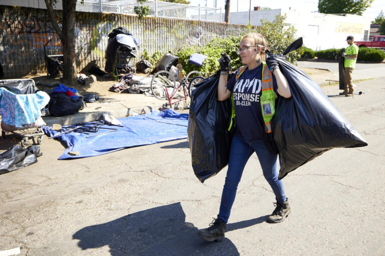 Amber Nastasia from Rapid Response Bio Clean cleans a homeless camp in Portland, Ore., Thursday, July 27, 2023. Cities across the U.S. are struggling with and cracking down on tent encampments as the number of homeless people grows, largely due to a lack of affordable housing. Homeless people and their advocates say sweeps are cruel and costly, and there aren't enough homes or beds for everyone.