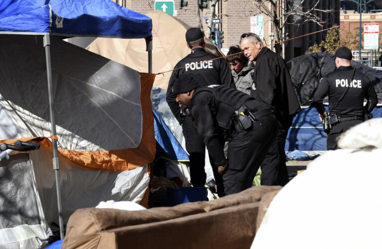 Police tell homeless people they need to leave the area during a sweep of an encampment in downtown Denver on Tuesday, Oct. 31, 2023. More cities across the U.S. are cracking down on homeless tent encampments that have grown more visible and become unsafe.