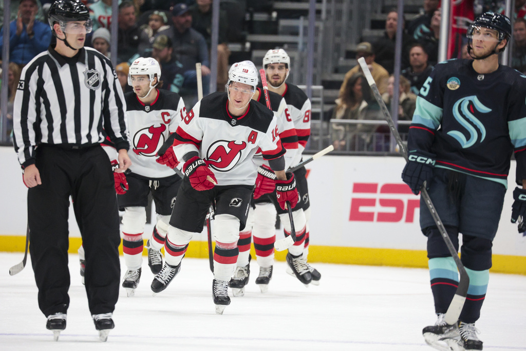 New Jersey Devils left wing Ondrej Palat (18) skates to the bench after scoring a goal, while Seattle Kraken left wing Andre Burakovsky, right, reacts during the first period of an NHL hockey game Thursday, Dec. 7, 2023, in Seattle.