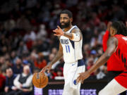 Dallas Mavericks guard Kyrie Irving gestures to teammates during the first half of their NBA basketball game against the Portland Trail Blazers on Friday, Dec. 8, 2023, in Portland, Ore.