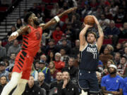 Dallas Mavericks guard Luka Doncic (77) shoots the ball as Portland Trail Blazers center Deandre Ayton defends during the first half of an NBA basketball game in Portland, Ore., Saturday, Dec. 16, 2023.