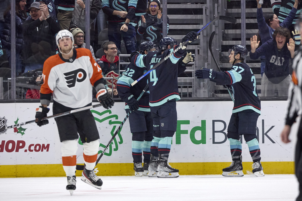 Seattle Kraken defenseman Justin Schultz (4) is congratulated by right wing Oliver Bjorkstrand (22) and center Yanni Gourde (37) after Schultz scored against the Philadelphia Flyers in overtime of an NHL hockey game Friday, Dec. 29, 2023, in Seattle.