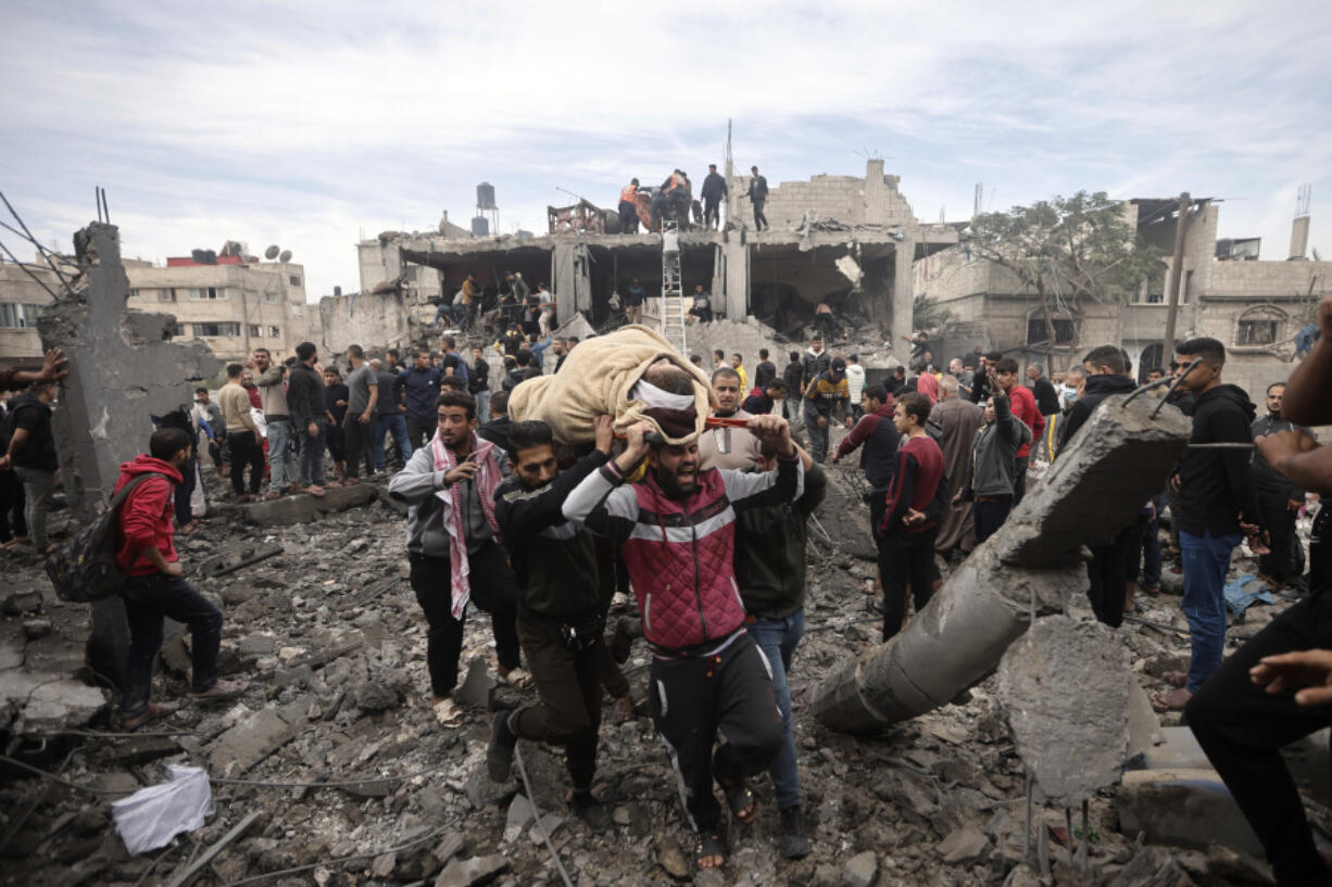 Palestinians evacuate a wounded woman following Israeli airstrikes in Khan Younis refugee camp, southern Gaza Strip, Thursday, Dec. 7, 2023.
