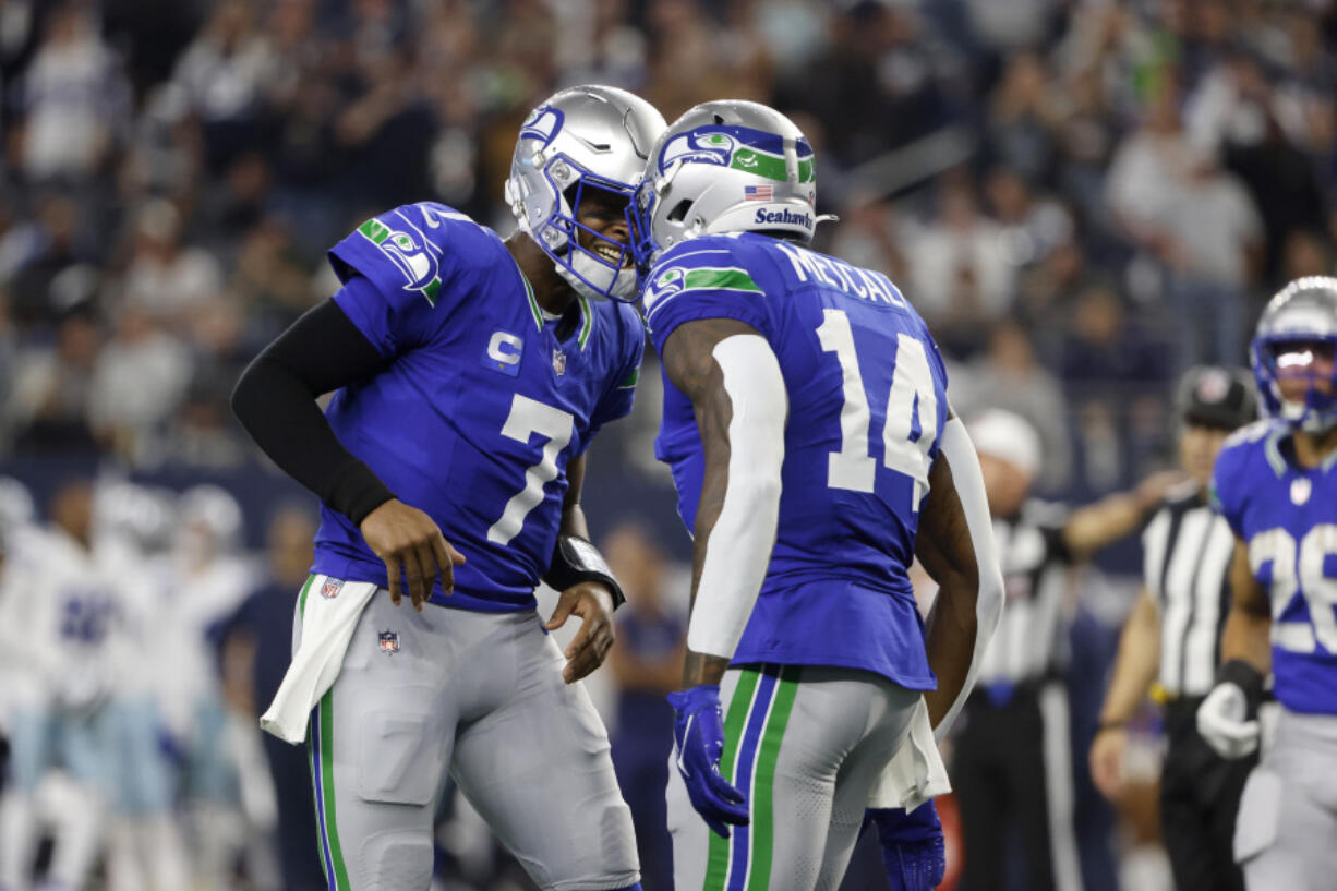 Seattle Seahawks quarterback Geno Smith (7) and wide receiver DK Metcalf (14) celebrate afer Metcalf caught a touchdown pass late in the first half of an NFL football game against the Dallas Cowboys in Arlington, Texas, Thursday, Nov. 30, 2023.