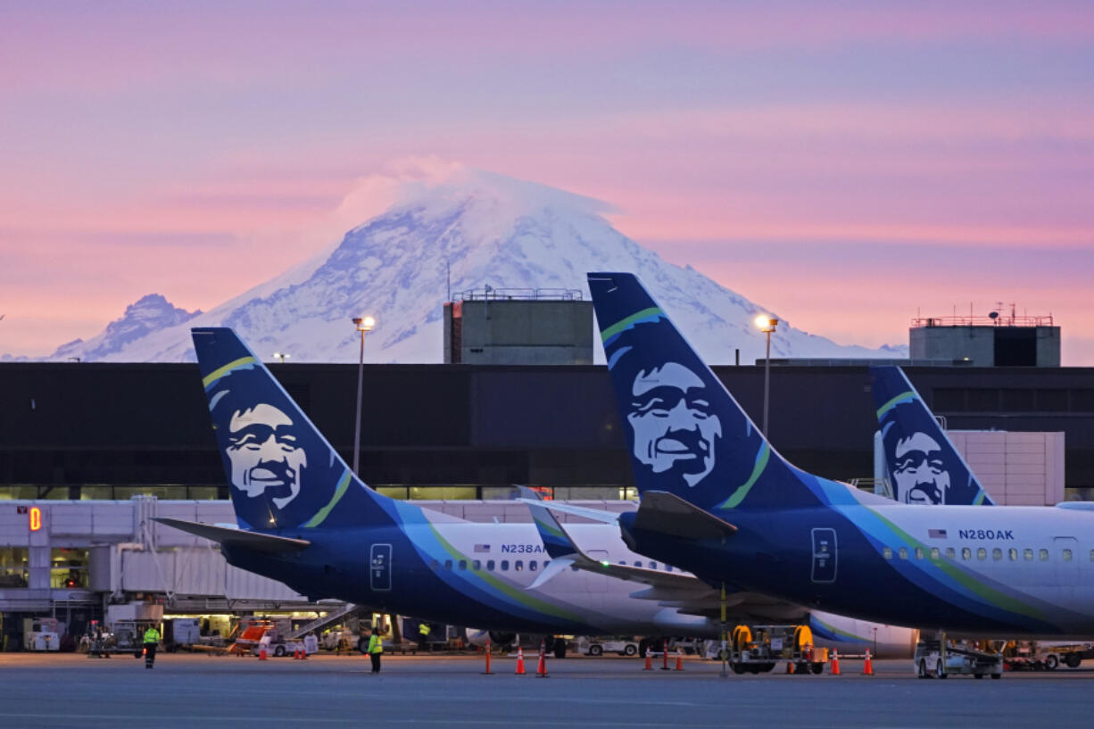 FILE - Alaska Airlines planes are shown parked at gates with Mount Rainier in the background at sunrise, March 1, 2021, at Seattle-Tacoma International Airport in Seattle. Alaska Air Group said Sunday, Dec. 3, 2023, that it agreed to buy Hawaiian Airlines in a $1 billion deal. (AP Photo/Ted S.
