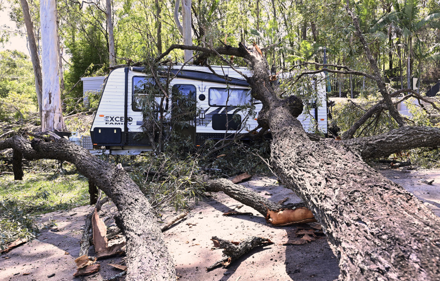 A fallen tree lays across a camping trailer near the Gold Coast, Australia Tuesday, Dec. 26, 2023. At least nine people have died in wild weather in the Australian eastern states of Queensland and Victoria, officials said on Wednesday.