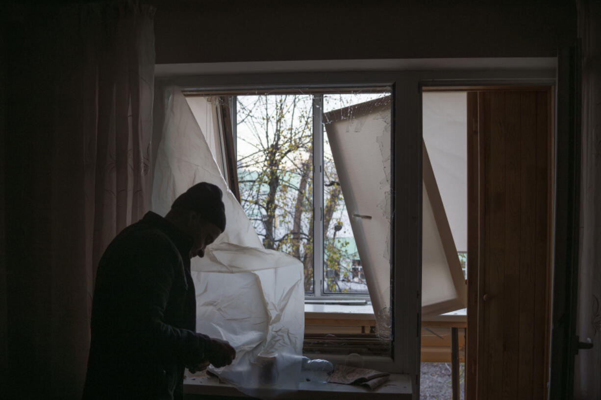 FILE - A man uses plastic to cover a broken window in his apartment following a Russian drone attack in Kyiv, Ukraine, Saturday, Nov. 25, 2023. On Monday, Dec. 4, the Biden Administration sent Congress an urgent warning about the need to approve tens of billions of dollars in military and economic assistance to Ukraine, saying that Kyiv&rsquo;s war effort to defend itself from Russia&rsquo;s invasion may grind to a halt without it.