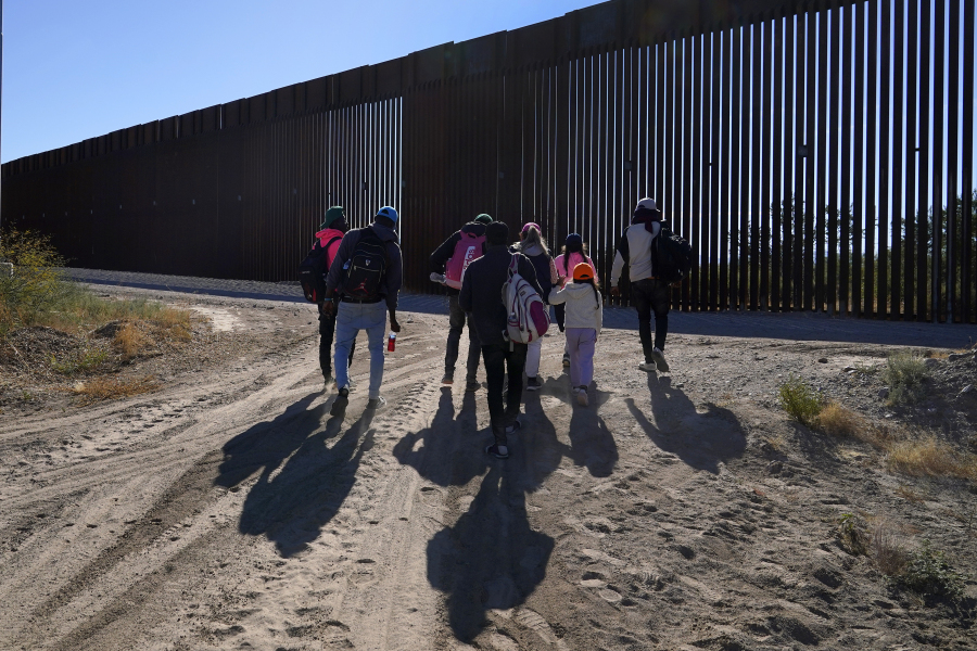 A group of migrants walk along the border in a remote part of the Arizona desert as they join hundreds of migrants gathering along the border Tuesday, Dec. 5, 2023, in Lukeville, Ariz. (AP Photo/Ross D.
