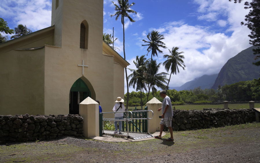 Kyong Son Toyofuku, left, her goddaughter Yunra Huh, center, and husband, Lance Toyofuku, right, walk into St. Philomena Church on July 18 during a tour of Kalaupapa, Hawaii. The church was expanded and used by St. Damien and his parishioners in the 1800s while he lived with and cared for leprosy patients banished to Kalaupapa.