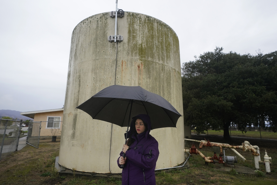 Ileana Miranda is interviewed in front of an old San Jerardo cooperative water tank in Salinas, Calif., Wednesday, Dec. 20, 2023. Some California farming communities have been plagued for years by problems with their drinking water due to nitrates and other contaminants in the groundwater that feeds their wells.