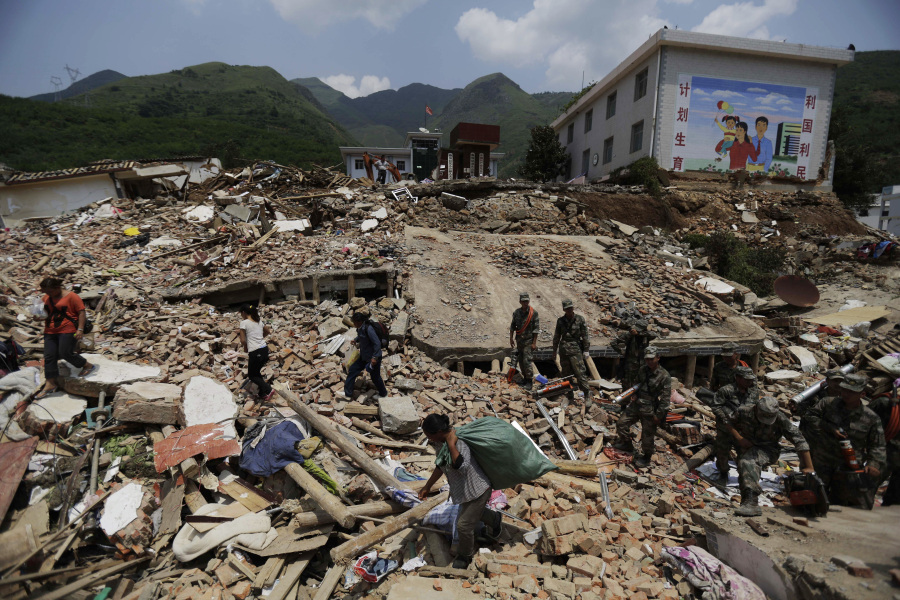 FILE - Villagers shift through the rubble of destroyed houses as rescuers search for missing persons in the quake-hit town of Longtoushan in Ludian County in southwest China&rsquo;s Yunnan Province Wednesday, Aug. 6, 2014.
