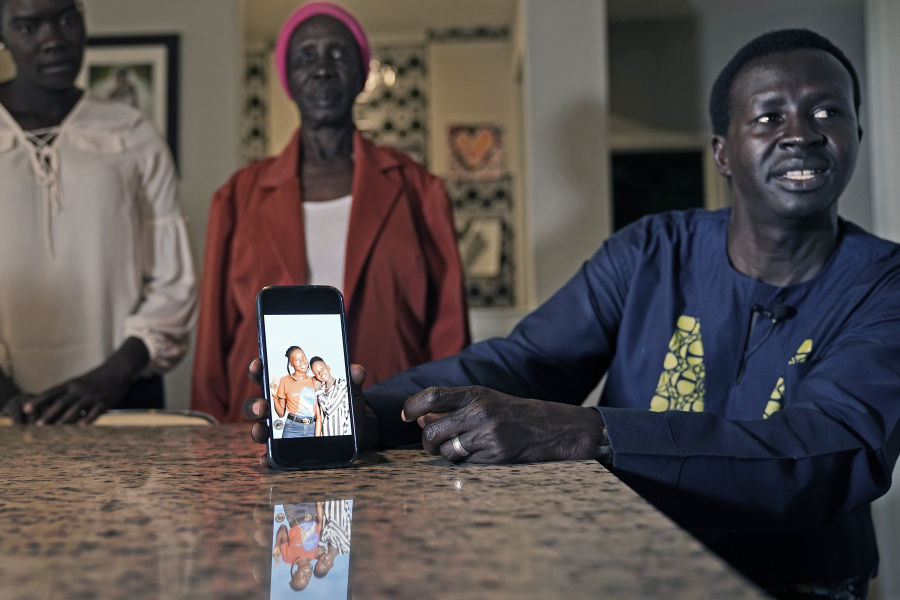 Jacob Mabil, right, speaks while showing a cell phone photo of hie nieces Nyanluak Deng, left, and Anyier Deng during an interview at his home Wednesday, Nov. 8, 2023, in Haslet, Texas. Looking on are the girl&rsquo;s grandmother Adeng Ajang and Mabil&rsquo;s wife Akuot Leek.