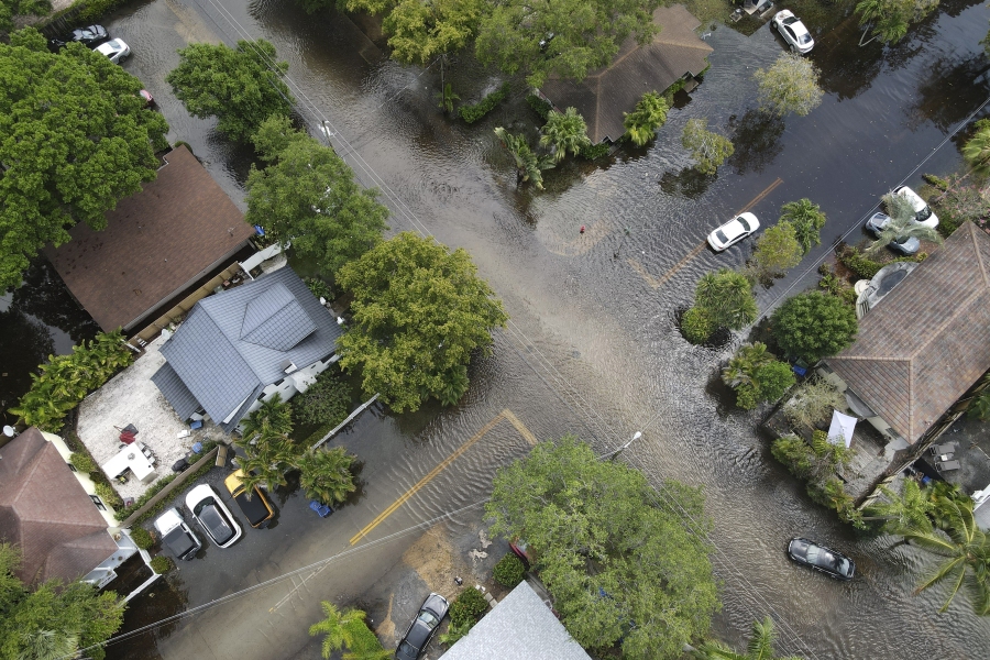 FILE - A pair of waterlogged cars sit abandoned in the road as floodwaters recede in the Sailboat Bend neighborhood of Fort Lauderdale, Fla., April 13, 2023. Flood risk and climate change are pushing millions of people to move from their homes, according to a new study by the risk analysis firm First Street Foundation.
