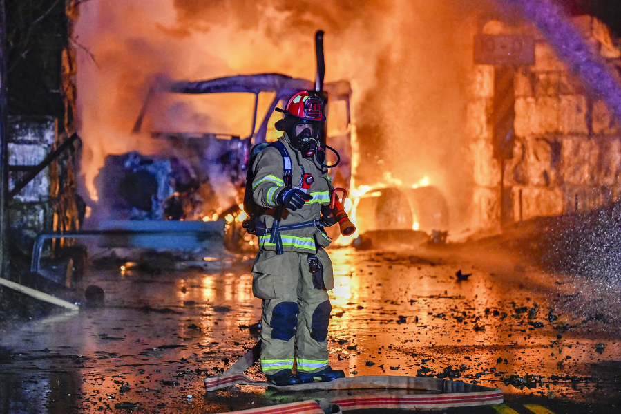 A firefighter works the scene after a tractor trailer truck struck a railroad bridge and burst into flames in Glenville, N.Y., Thursday, Dec. 21, 2023. Authorities believed the truck contained gas containers. (Peter R.