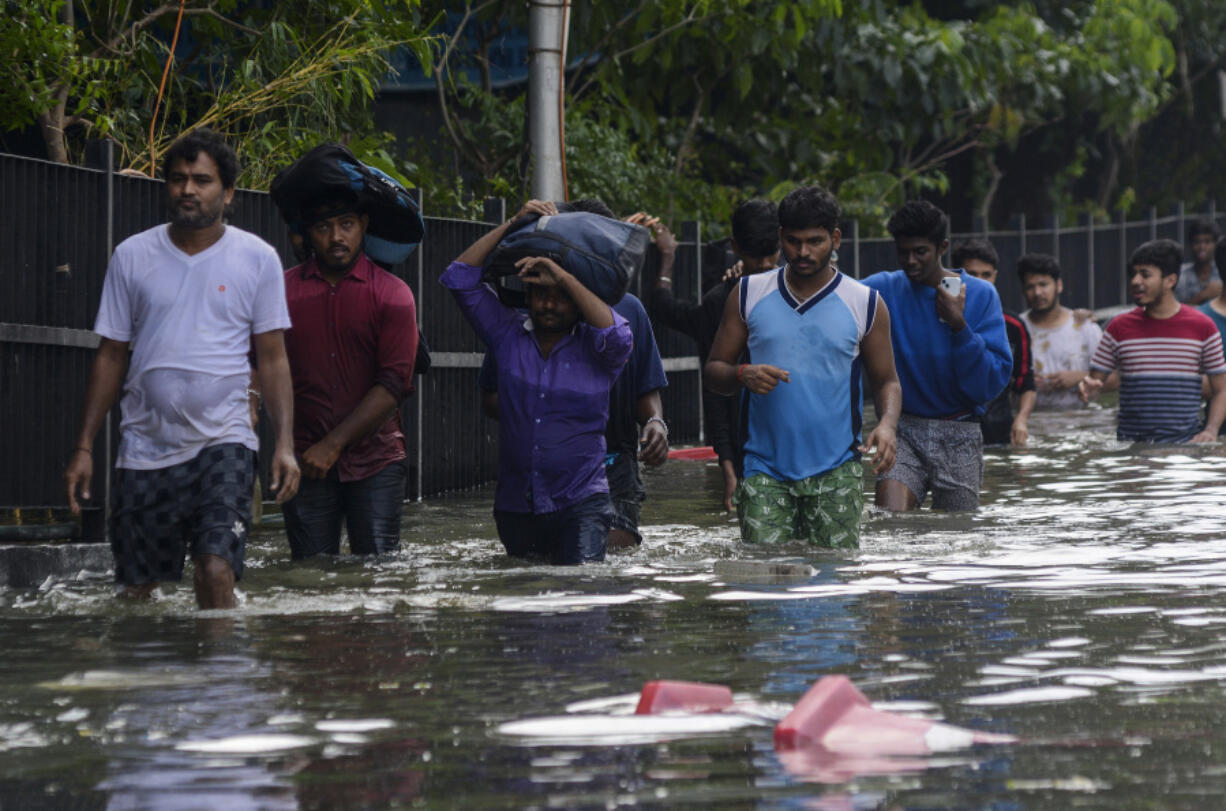 People wade through flood waters following heavy rains along the Bay of Bengal coast in Chennai, India, Tuesday, Dec.5, 2023. Tropical Storm Michaung began making landfall along India&rsquo;s southeastern coastline Tuesday, bringing with it torrential rains and strong winds.
