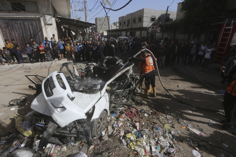 Palestinians stand around a car targeted in an Israeli airstrike on a car in Rafah, Gaza Strip, Friday, Dec.