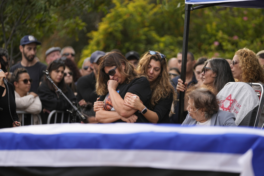 Family and friends of Alon Shamriz, 26, mourn over his grave during his funeral in the cemetery of Kibbutz Shefayim, southern Israel, Sunday Dec. 17, 2023.