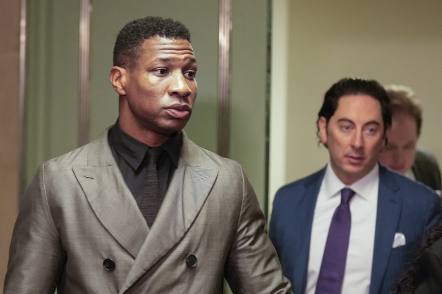 Jonathan Majors, left, enters a courtroom at the Manhattan criminal courts in New York, Monday, Dec. 18, 2023. The actor is accused of assaulting his then-girlfriend as the two struggled over a phone in the back seat of a chauffeured car.