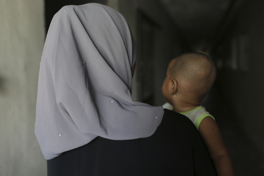Rohingya child bride, T, age 16, holds her son in Kuala Lumpur, Malaysia, on Oct. 5, 2023. T left Bangladesh for Malaysia in 2022 for an arranged marriage with an older man. During her journey from Bangladesh, she was abused by a trafficker. She says her husband verbally abuses her and doesn&rsquo;t let her leave their apartment.