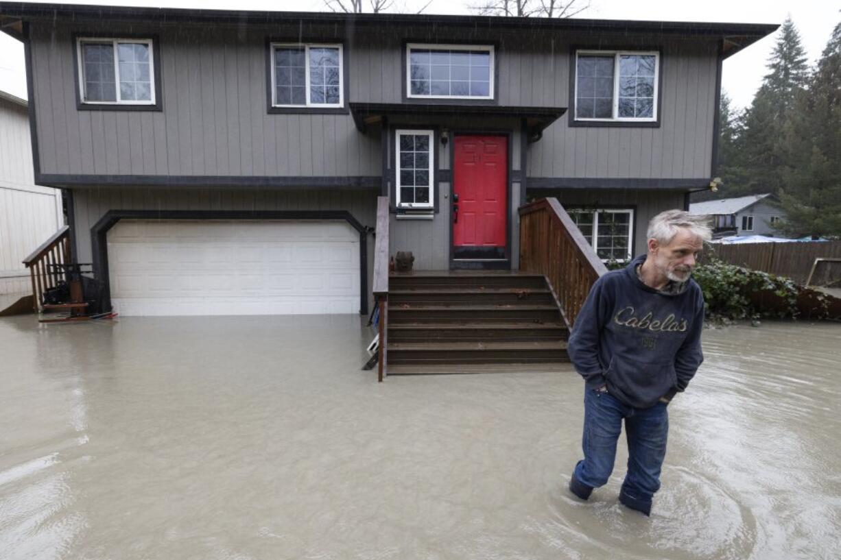 Bernie Crouse wades through water outside his home after the nearby South Fork Stillaguamish River crested early in the morning flooding several houses in this neighborhood, Dec. 5, 2023,  in the Arlington area of Seattle, Washington. Crouse got his dog Max out of the basement as it began flooding, after getting a call from another neighbor.