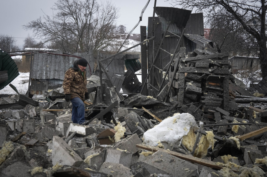 A local resident passes by debris at the site of a private house ruined in the Russian missile attack in Kyiv, Ukraine, Monday, Dec. 11, 2023.