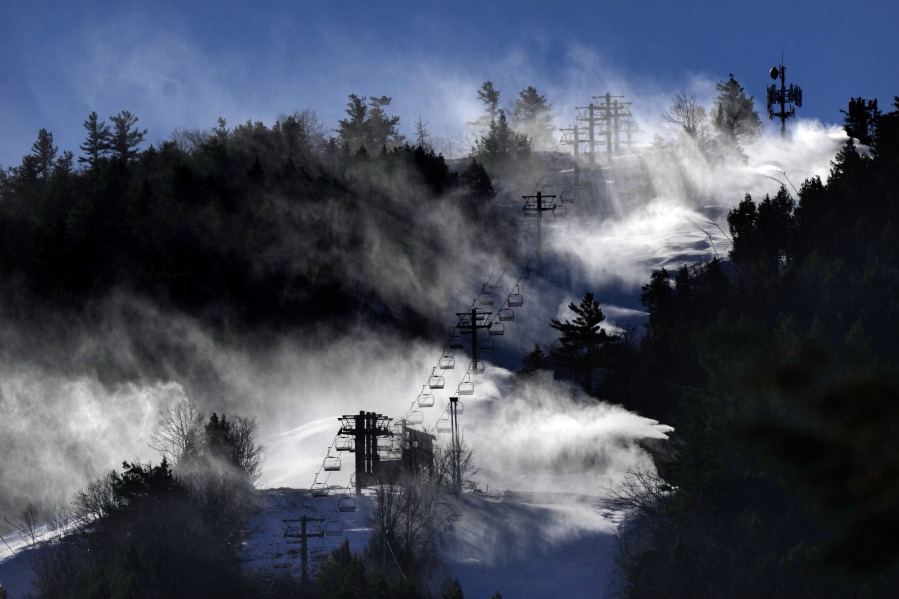 Man-made snow is blown from snowmaking equipment near the summit of Pleasant Mountain ski resort, Thursday, Dec. 21, 2023, in Bridgton, Maine. The New England ski industry is working to recover from a disastrous rain storm that washed away much of the snow just before the Christmas vacation season. (AP Photo/Robert F.