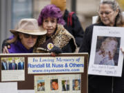 FILE - Ellen Isaacs, left, and Lee Nuss, center, both from Florida, hold each other and sing a song of remembrance for Randall M. Nuss, Lee&rsquo;s husband, during a protest with other advocates for opioid victims outside the U.S. Department of Justice, Dec. 3, 2021, in Washington. Families who lost loved ones to overdose are divided over OxyContin maker Purdue Pharma&rsquo;s plan to settle lawsuits over the toll of opioids with governments. It could provide billions to address an overdose epidemic and pay some victims. But it would also protect members of the Sackler family who own the company from future lawsuits.